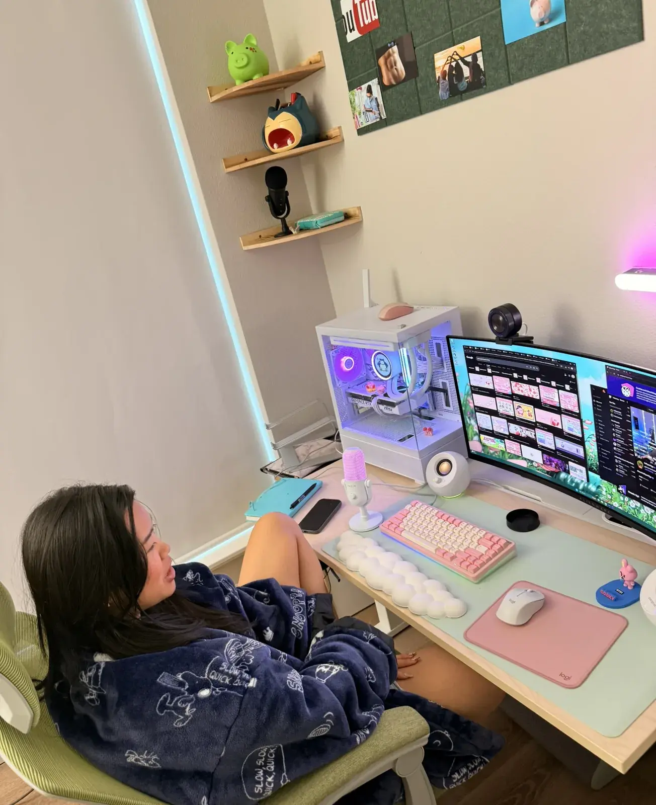 Kimberly at her desk in a blanket, her white PC glowing beside her pink keyboard.