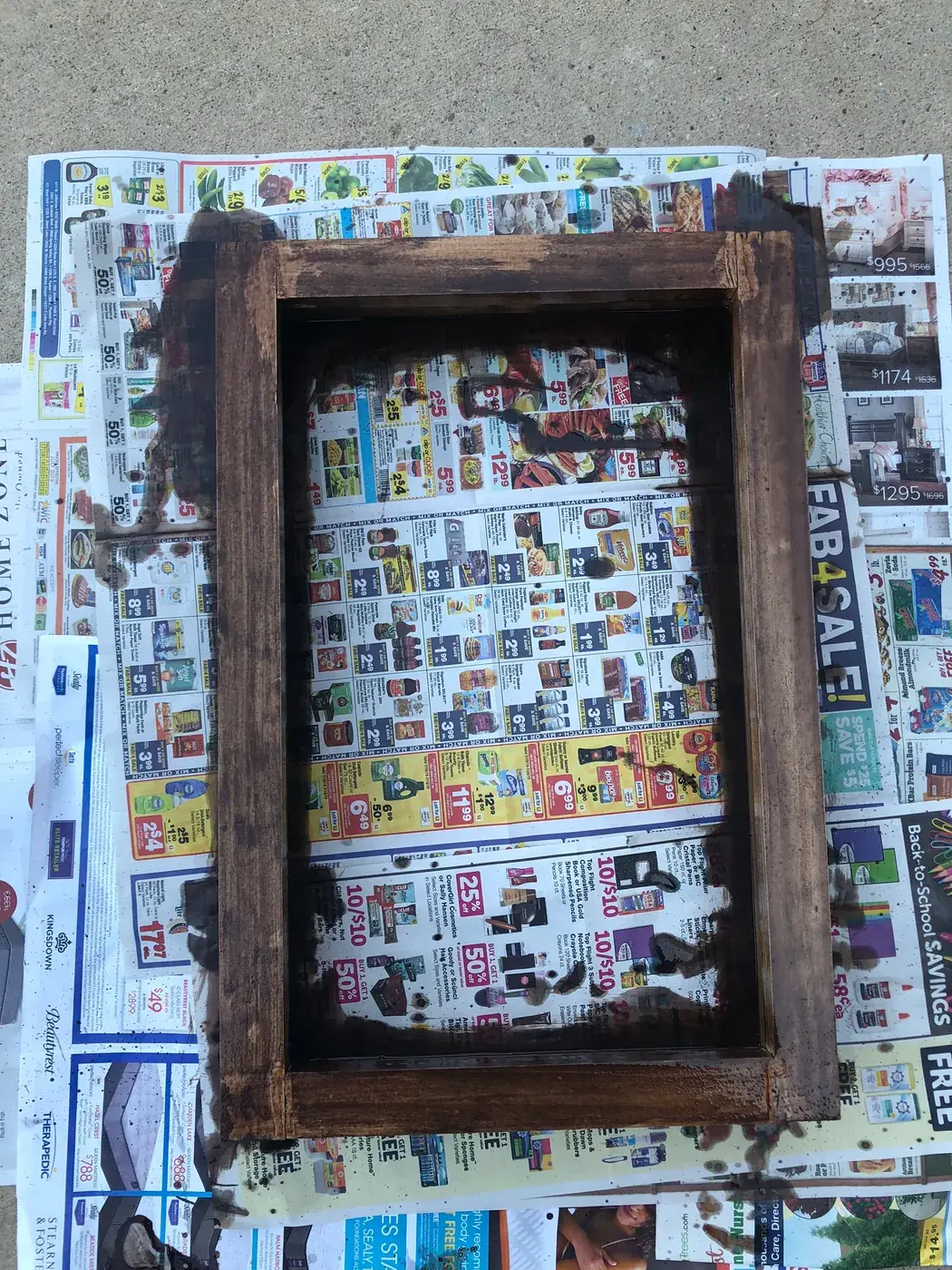 The frame stained dark, drying on newspaper.