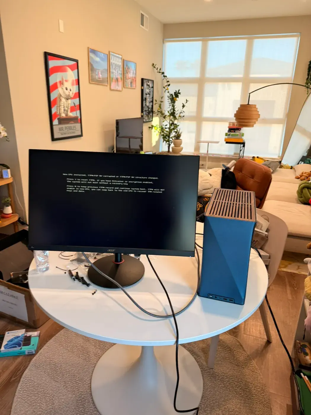 The new small PC in a blue case next to the old 27-inch monitor, booting up.