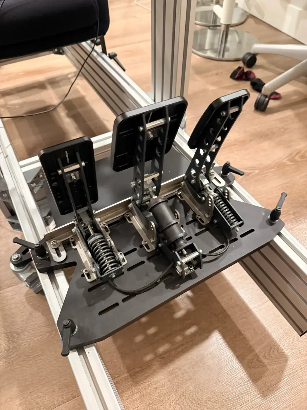Three Heusinkveld pedals bolted to the aluminum chassis.